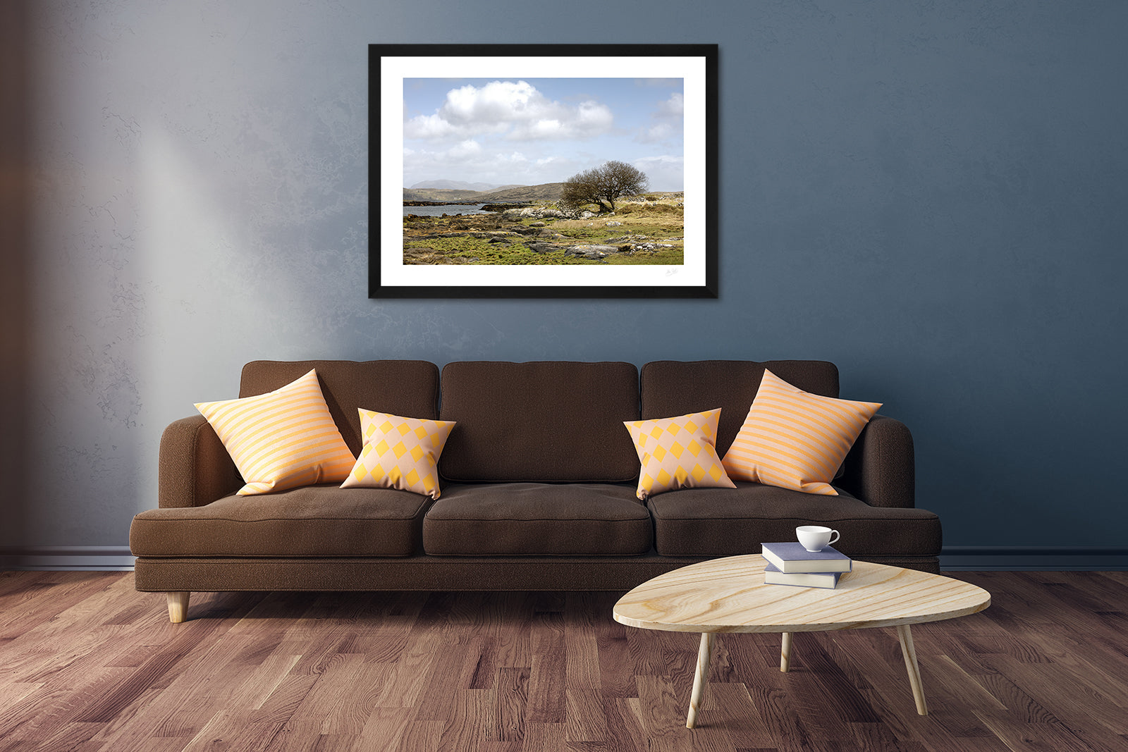 a framed fine art photograph of the rugged Connemara landscape as seen from Canower in County Galway, Ireland hanging on a wall above a brown sofa and a wooden coffee table