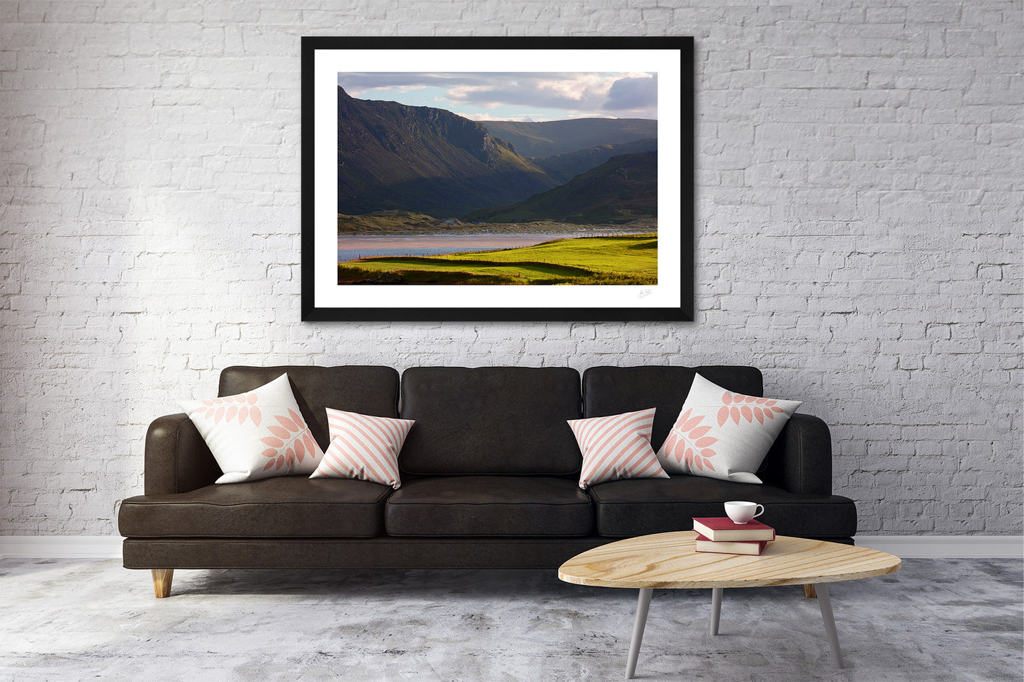 a fine art framed photograph view of Maghera Strand in Co. Donegal from across Loughros Beg Bay with Owenwee valley and waterfall in the background. Hanging on a wall above a brown sofa in a living room.