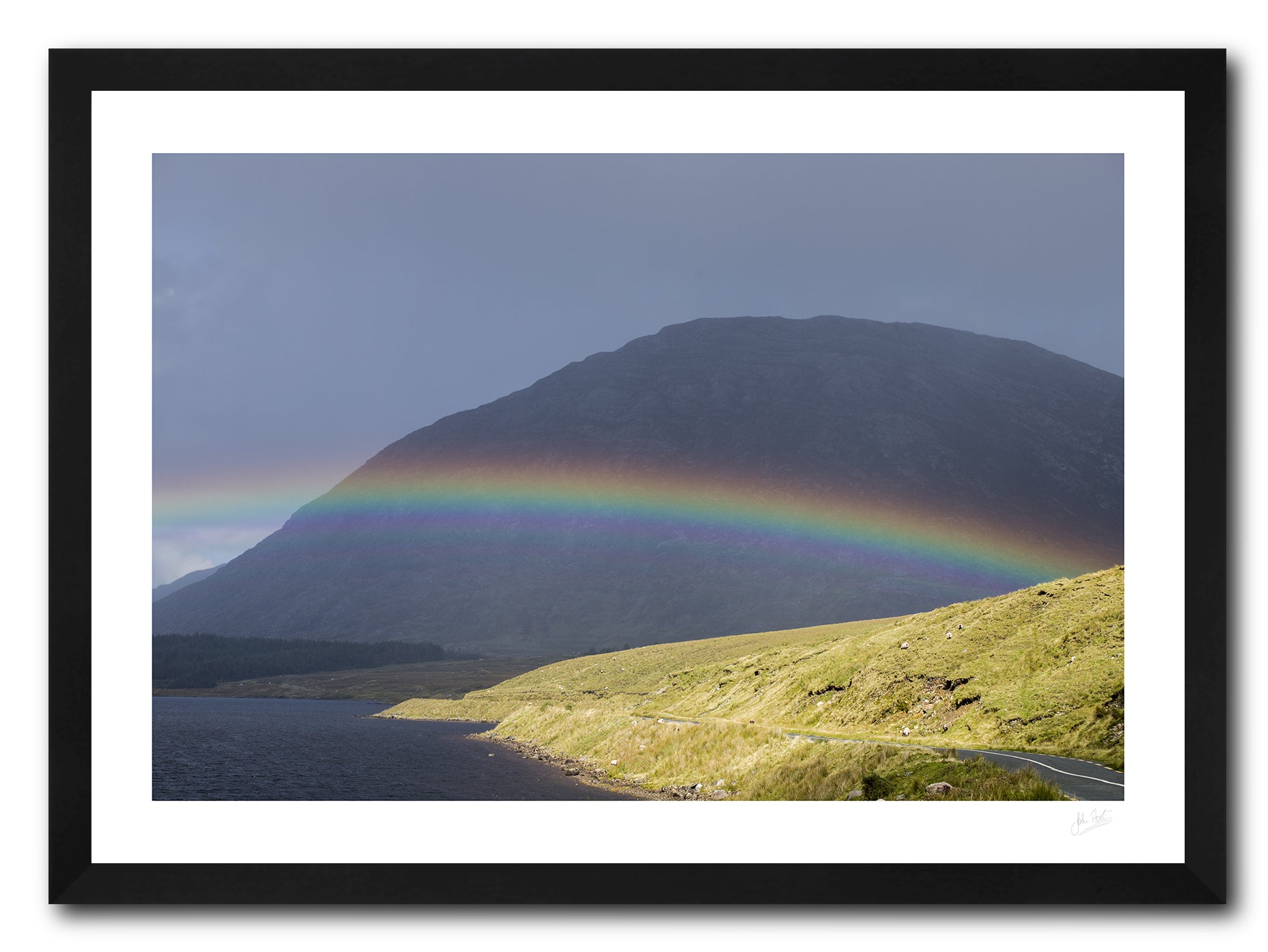a framed fine art photographic print of a rainbow stradling Lough Inagh, Connemara as the rain shower moves away toward Letterbreckaun Mountain, available to buy online