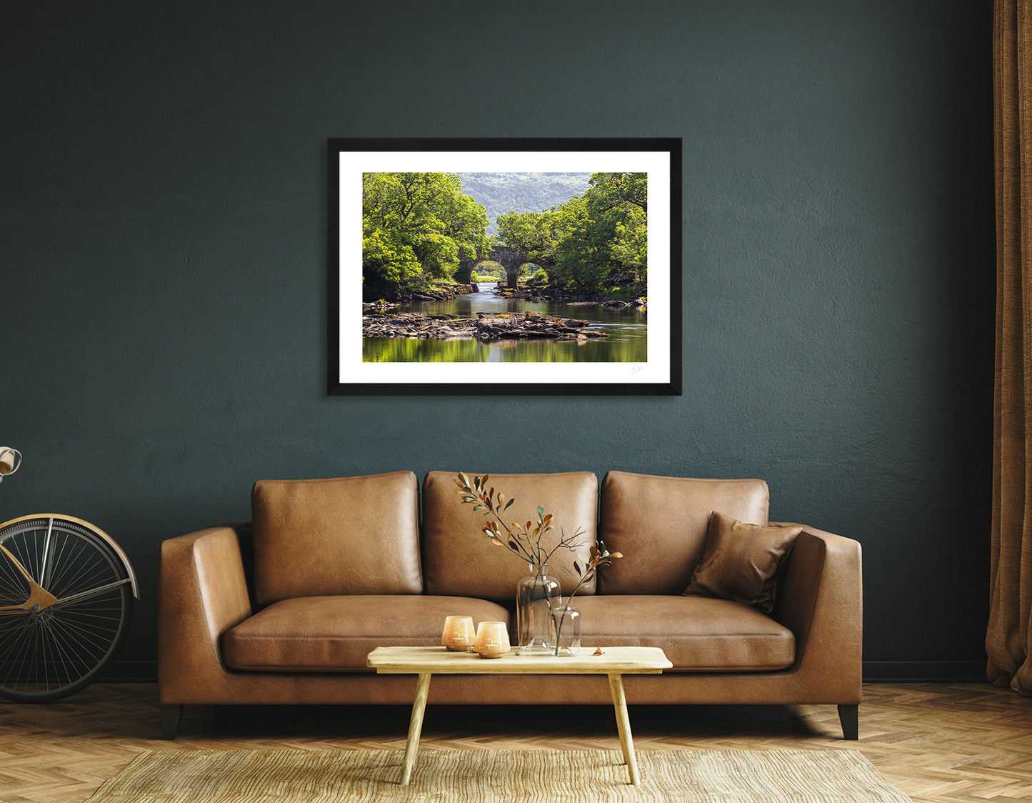 a framed fine art photographic print of the Old Weir Bridge a the Meeting of the Waters in Killarney National Park, hanging on a wall above a sofa and coffee table