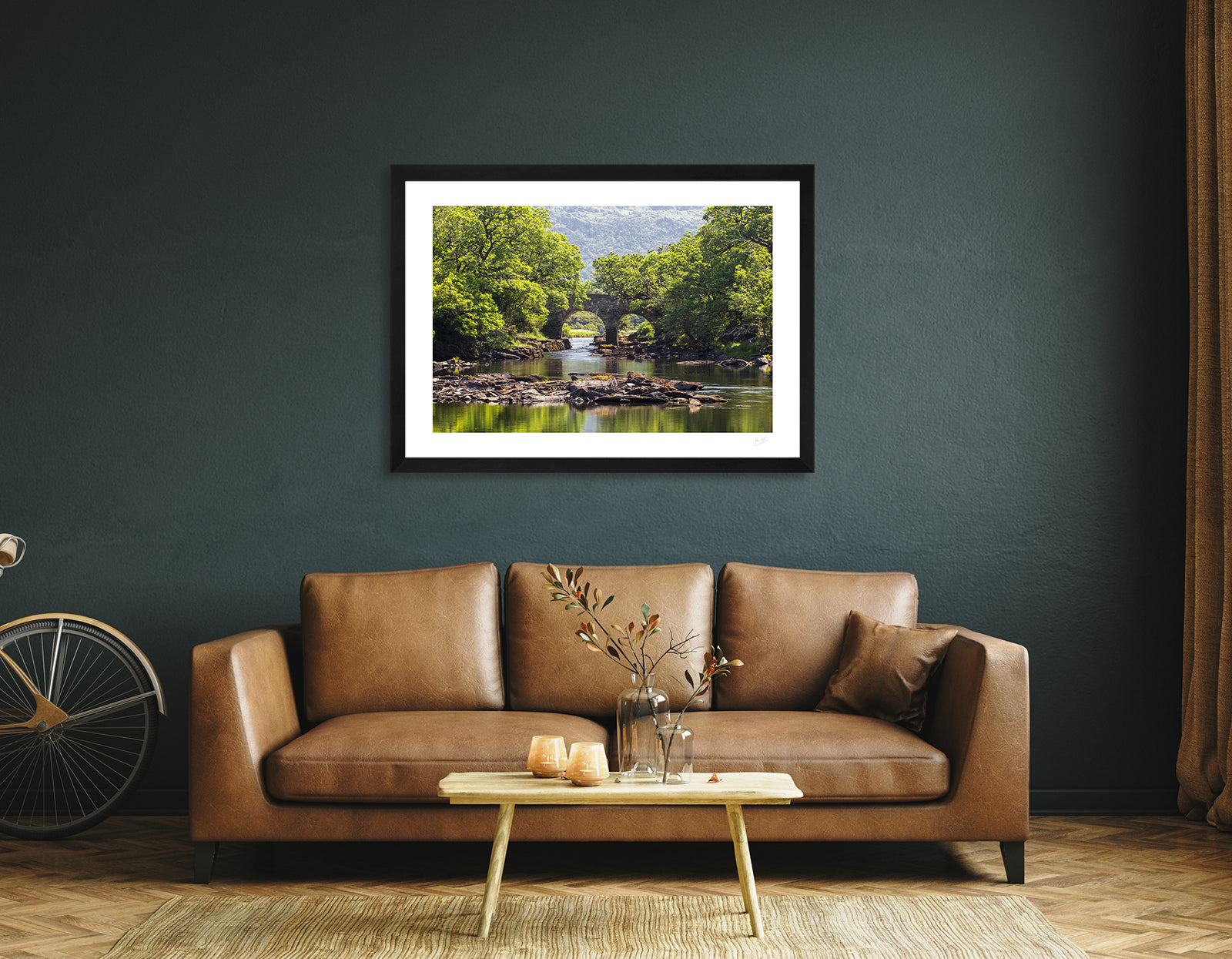 a framed fine art photographic print of the Old Weir Bridge a the Meeting of the Waters in Killarney National Park, hanging on a wall above a sofa and coffee table