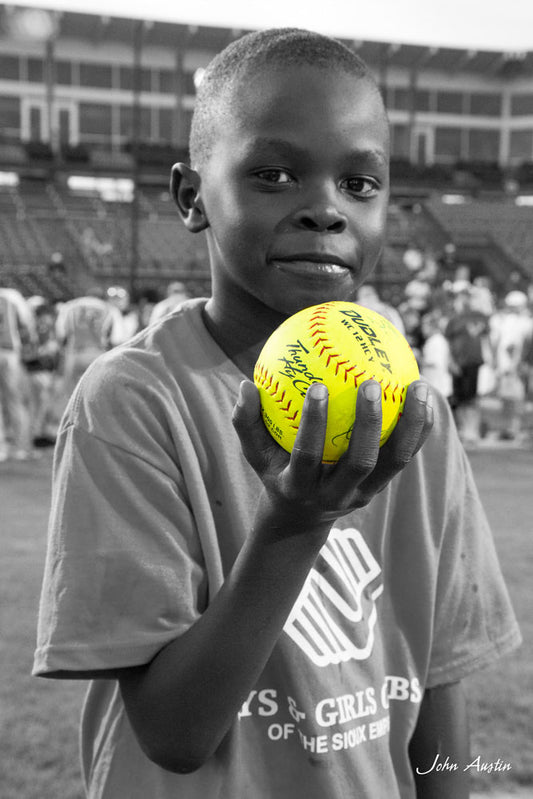 A young boy holds an autgraphed softball in his hand at a promotional event for USA Softball