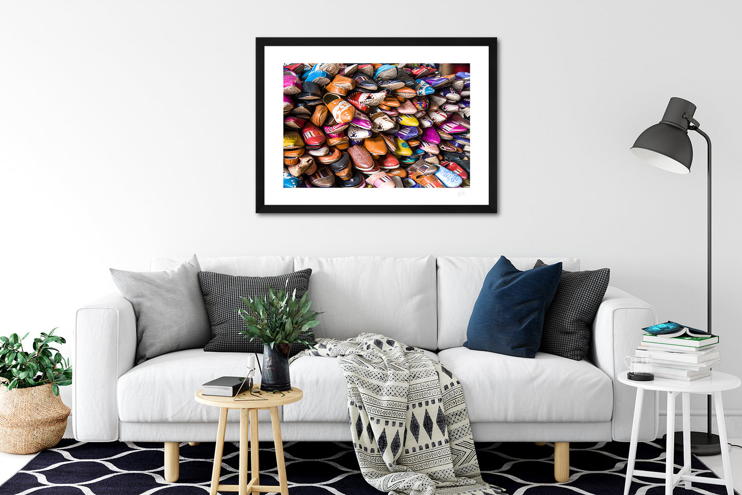 a framed fine art photographic print of a pile of different coloured shoes for sale in a leather shop in Tangier, Morocco, hanging on a wall above a sofa