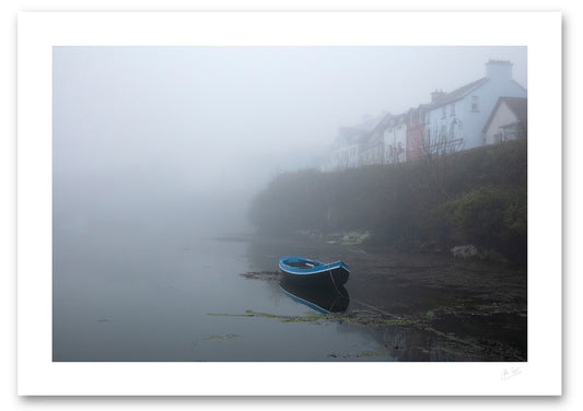 a fine art photograph of a rowing boat moored in Roundstone Harbour, Connemara in dense fog with only a few of the towns buildings visible