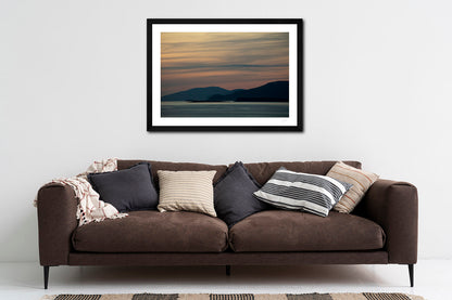 a framed print of Clare and Achill Islands silhouetted in front of a palette of twilight colour, hanging above a sofa