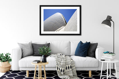 a framed fine art photographic print of the roof of the Sydney Opera House showcasing its curves and tiles, hanging on a wall above a sofa