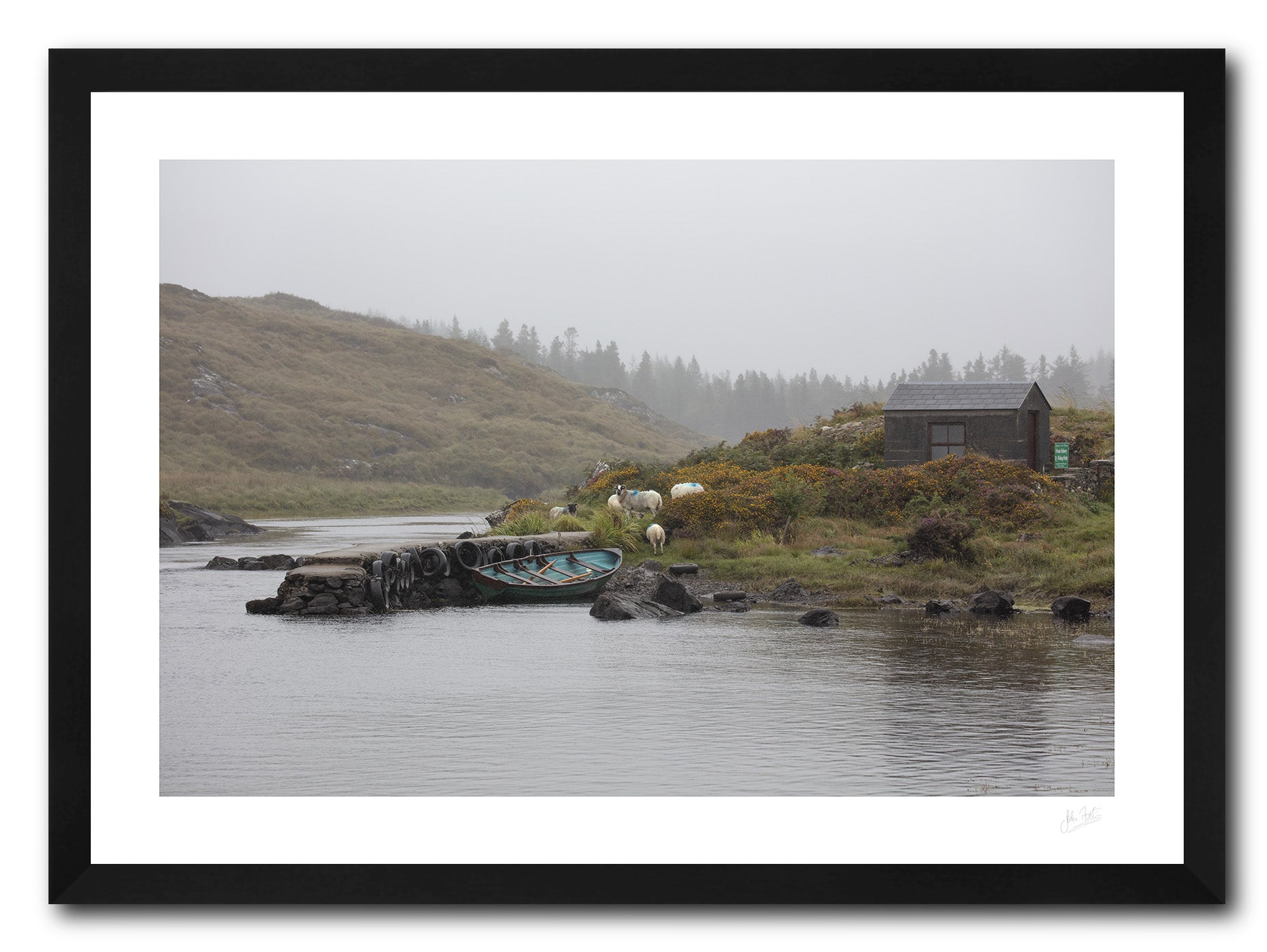 a framed fine art photograph of a fishing hut and row boat mooring on the Owenmore River on a rainy day with a few grazing sheep