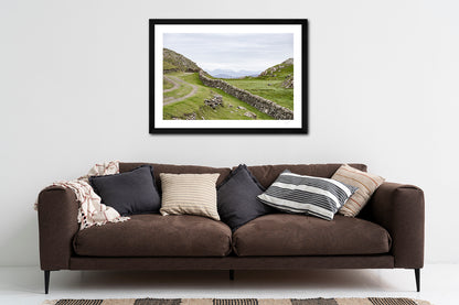framed fine art print of the 12 Bens mountain range as seen from Inishboffin Island hanging on a wall above a brown sofa