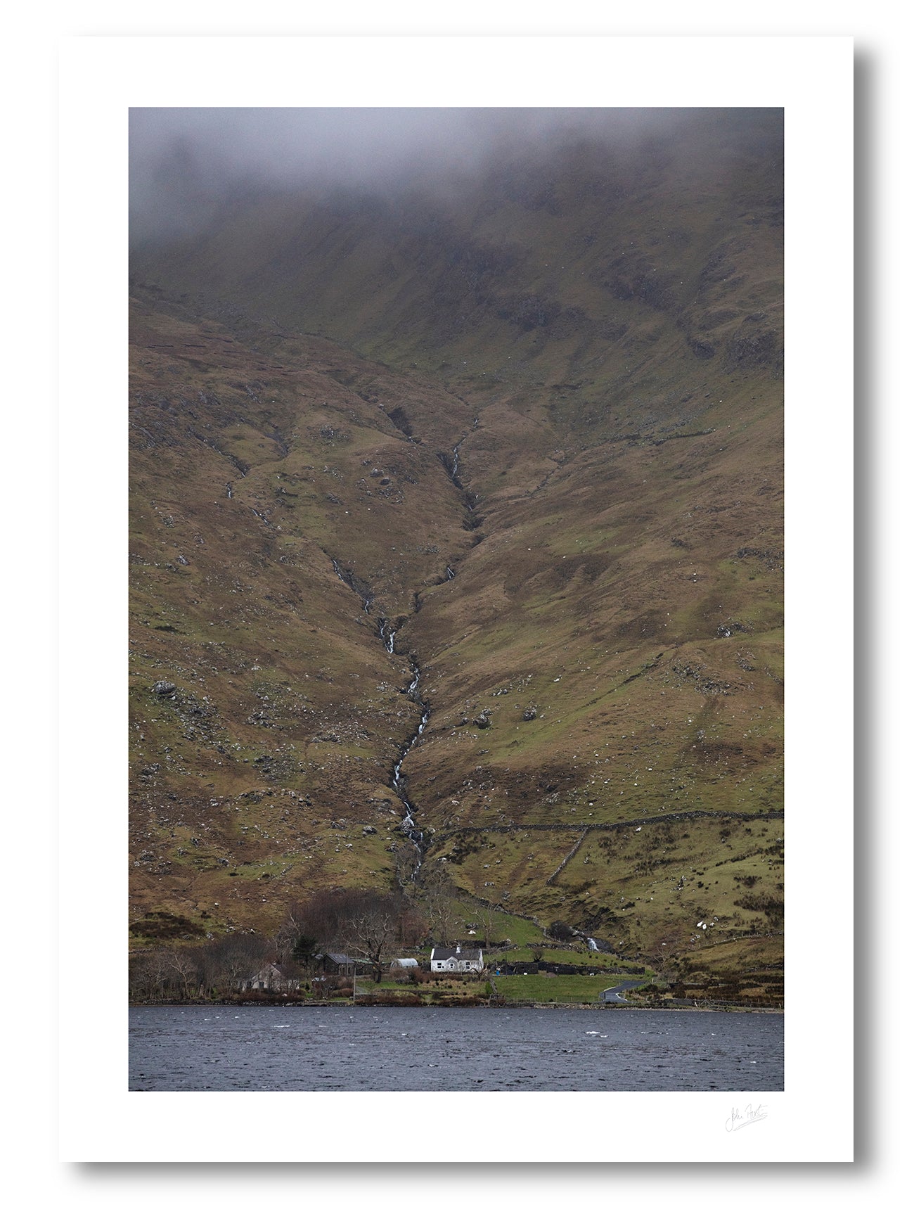 print of a lakeside farm house at the foot of Benchoona mountain in Connemara, provides a sense of scale as the mountain rises from the lake to the clouds