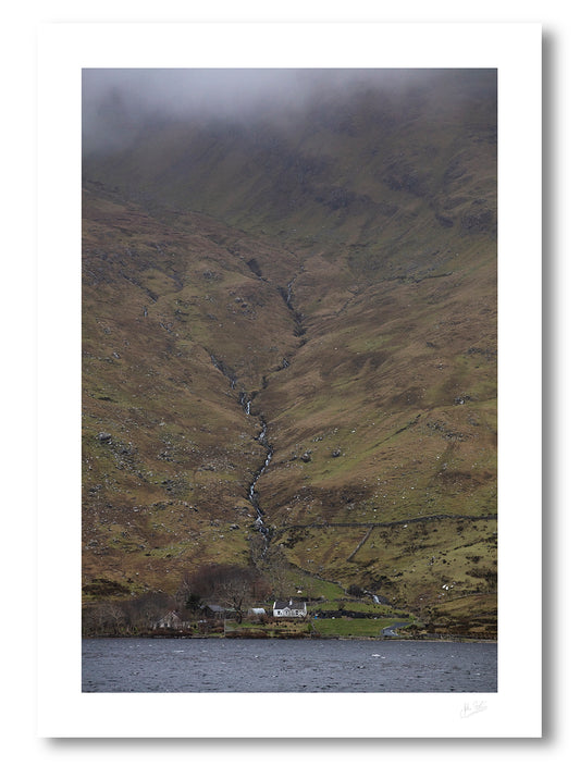print of a lakeside farm house at the foot of Benchoona mountain in Connemara, provides a sense of scale as the mountain rises from the lake to the clouds
