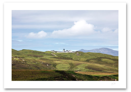 unframed print of a distant Clare Lighthouse with green hills and clouds in the sky