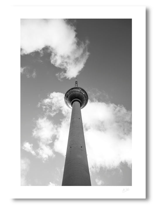 unframed print of Berlin's TV tower from below touching the clouds in the sky