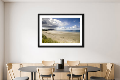 a framed fine art photographic print of rain heading to Glassilaun Beach, Connemara on a sunny autumn afternoon, hanging on a wall above a dining table
