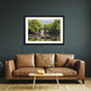 a framed fine art photographic print of the Old Weir Bridge a the Meeting of the Waters in Killarney National Park, hanging on a wall above a sofa and coffee table