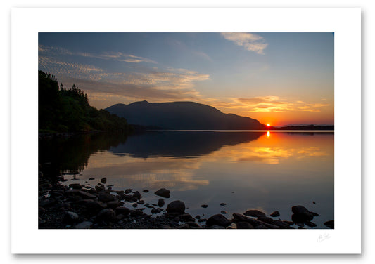 unframed fine art print of a sunset across a still Muckross Lake from a stoney beach with Shehy mountain in the background
