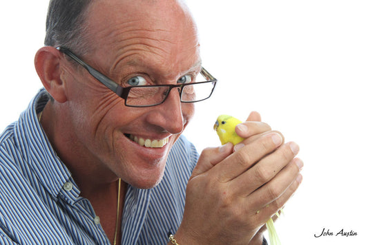 headshot of a man holding a budgy in his hands