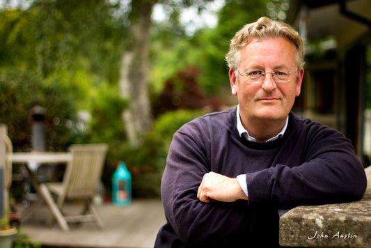 outdoor headshot of a Alan leaving against a wall