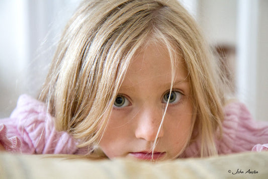 a headshot of a young girl resting her head on the arm of a sofa