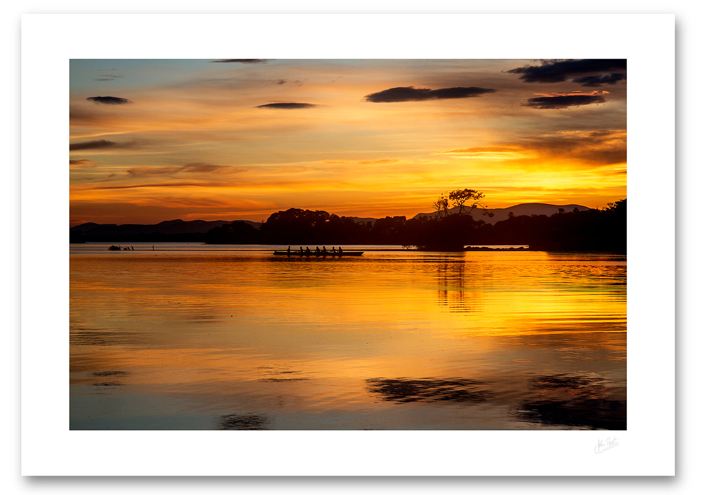 an unframed fine art photographic print of a crew of rowers on Lough Leane, Killarney surrounded by the beautiful colours of a summer sunset reflected in the water