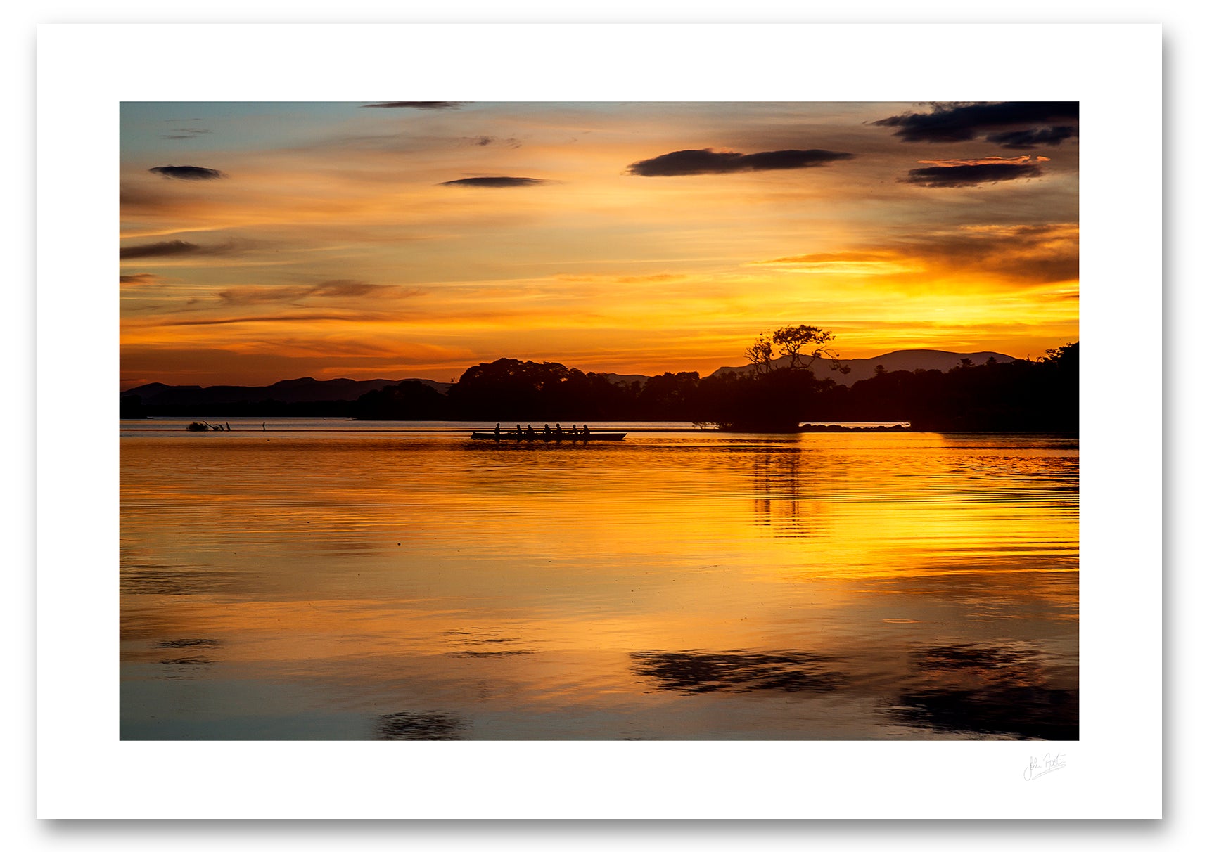 an unframed fine art photographic print of a crew of rowers on Lough Leane, Killarney surrounded by the beautiful colours of a summer sunset reflected in the water